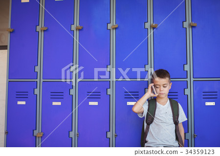 Boy talking on mobile phone against lockers 34359123