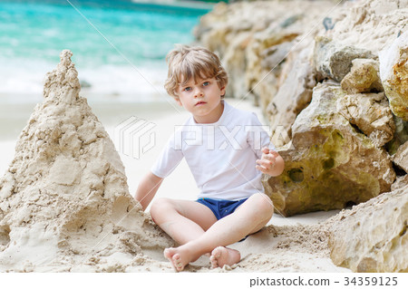 Little kid boy building sand castle on tropical 34359125