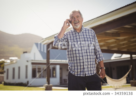 Senior man talking on mobile phone outside his house Senior man talking on mobile phone outside his house 34359138