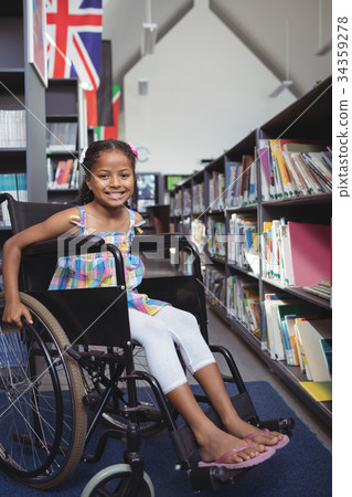 Smiling girl sitting on wheelchair in library 34359278