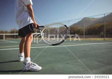Girl holding tennis racket while standing on court 34359321