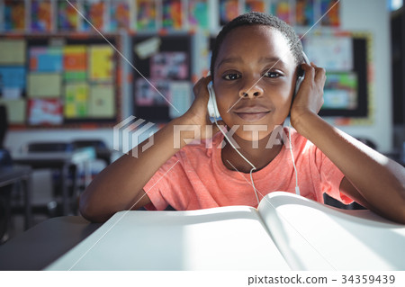 Boy listening music with headphones at desk 34359439
