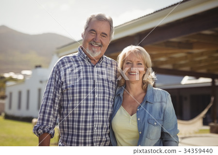 Smiling senior couple standing together in garden Smiling senior couple standing together in garden 34359440