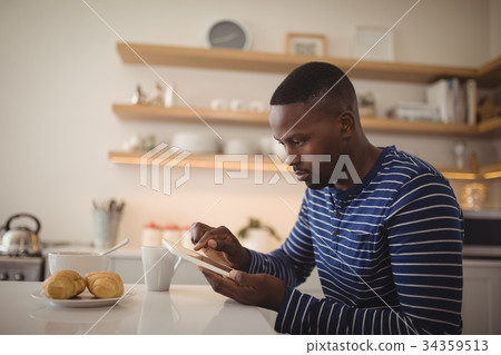 Man using a digital tablet in kitchen Man using a digital tablet in kitchen 34359513