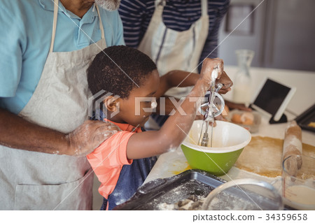 Boy learning to whisk the eggs while preparing cookies Boy learning to whisk the eggs while preparing cookies 34359658