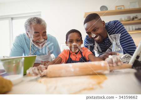 Boy preparing cookie dough with his father and grandfather in kitchen 34359662