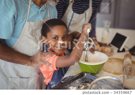 Boy learning to whisk the eggs while preparing cookies 34359667