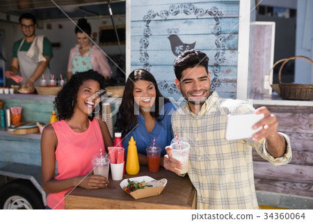 Friends taking selfie from mobile phone in food truck van 34360064