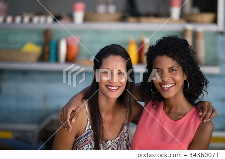 Smiling friends sitting with arm around 34360071