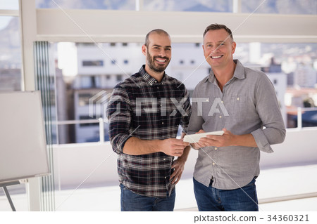 Portrait of happy colleagues holding digital tablet 34360321