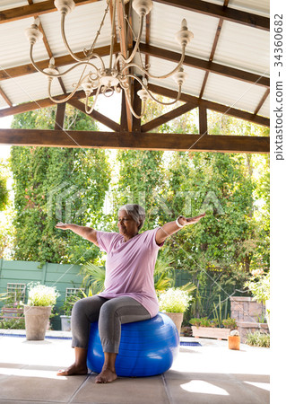 Full length of senior woman with arms outstretched sitting on exercise ball Full length of senior woman with arms outstretched sitting on exercise ball 34360682
