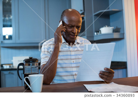 Man reading document walking talking on phone 34360893