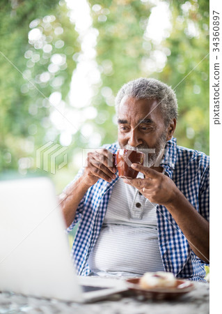 Man having drink while using laptop 34360897
