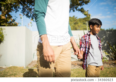 Father and son holding hands during sunny day Father and son holding hands during sunny day 34360923