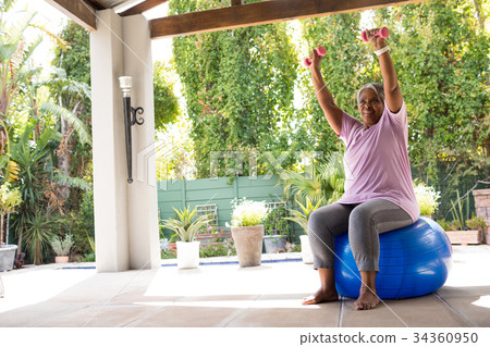 Woman with arms raised holding dumbbells Woman with arms raised holding dumbbells 34360950