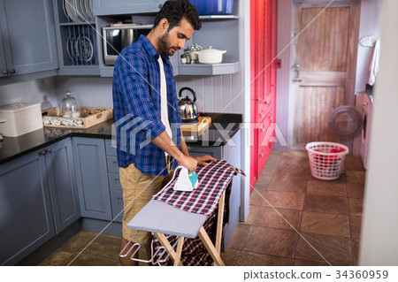 Side view of young man ironing shirt Side view of young man ironing shirt 34360959