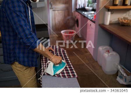 Midsection of man ironing shirt 34361045
