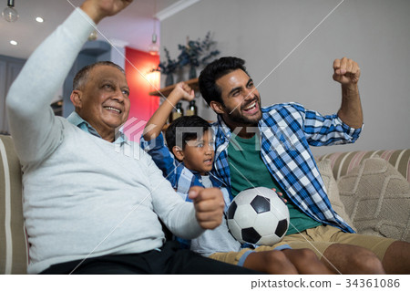 Happy family with arms raised watching soccer match Happy family with arms raised watching soccer match 34361086