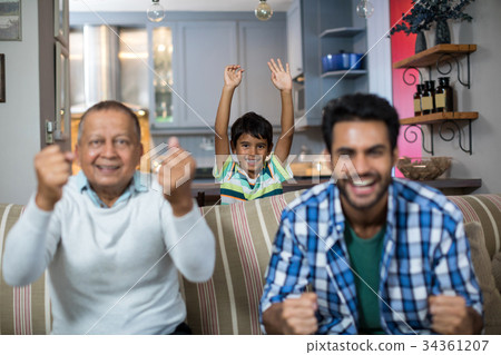 Happy family clenching fist while watching soccer match 34361207