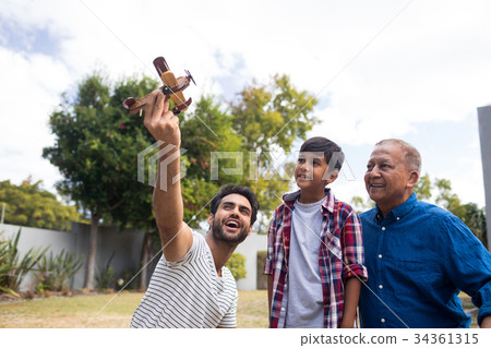 Boy with grandfather looking at man holding toy airplane 34361315