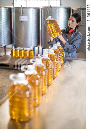 Female worker checking oil bottles Female worker checking oil bottles 34361435