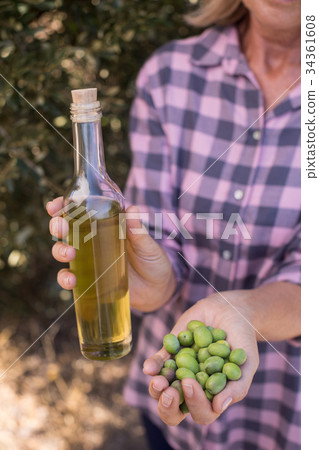 Woman holding olive oil and harvested olives 34361608