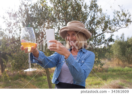 Woman taking a photo of wine glass in olives farm Woman taking a photo of wine glass in olives farm 34361609