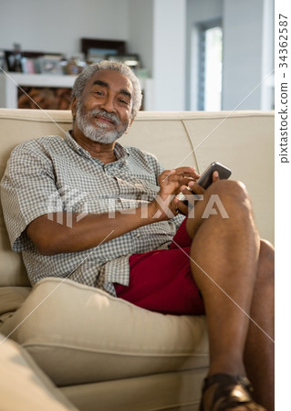 Senior man using mobile phone in the living room 34362587