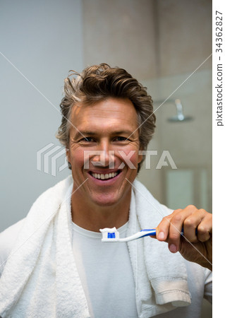 Man holding toothbrush with toothpaste in bathroom Man holding toothbrush with toothpaste in bathroom 34362827