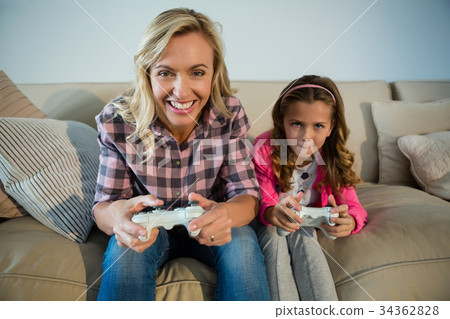 Mother and daughter playing video game in the living room Mother and daughter playing video game in the living room 34362828