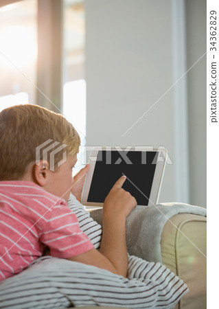 Boy using digital tablet in the living room Boy using digital tablet in the living room 34362829