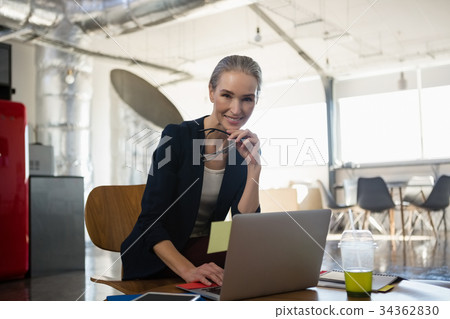 Portrait of smiling young woman using laptop in office Portrait of smiling young woman using laptop in office 34362830