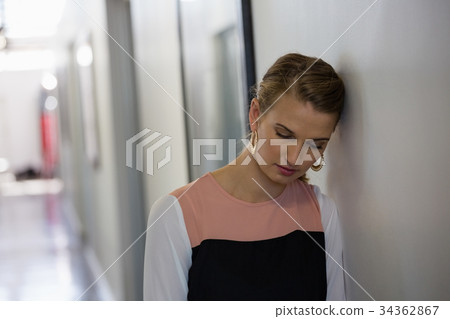 Sad young businesswoman leaning on wall 34362867