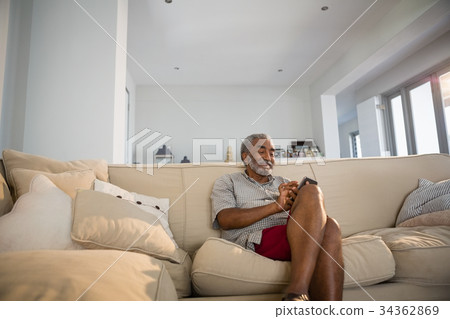 Senior man using mobile phone in the living room 34362869