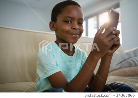 Boy using mobile phone in the living room at home Boy using mobile phone in the living room at home 34363060