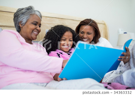 Family watching photo album together in living room 34363332