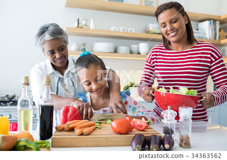 Grandmother assisting granddaughter to chop vegetables in kitchen Grandmother assisting granddaughter to chop vegetables in kitchen 34363562