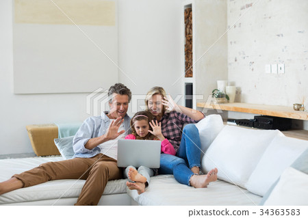 Family having a video call on laptop in living room 34363583