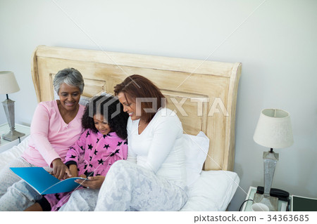 Family watching photo album together in living room 34363685