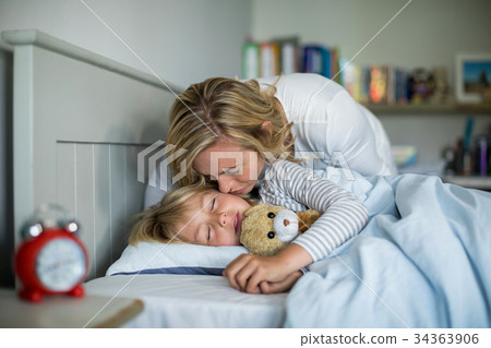 Mother kissing her daughter in the bedroom 34363906