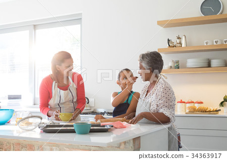 Girl feeding food to her grandmother in kitchen 34363917