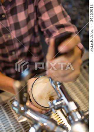 Midsection of barmaid preparing drink 34363918