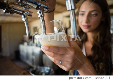 Close-up of barmaid pouring beer from tap in glass 34364001