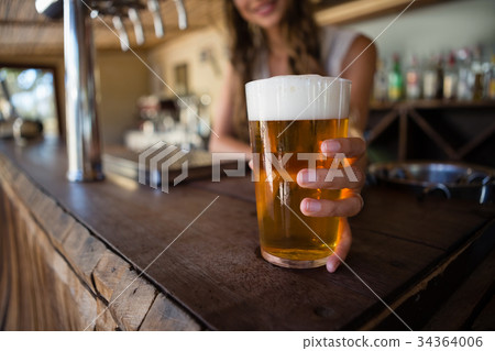 Barmaid holding beer glass 34364006