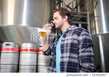 Low angle view of man examining beer 34364007