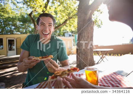 Happy man looking at friend while having pizza Happy man looking at friend while having pizza 34364116