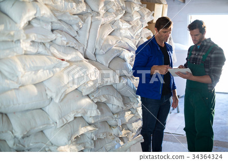 Coworkers discussing while standing barley sacks 34364324