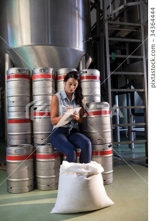 Female worker writing on clipboard in factory 34364444