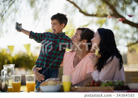 Family taking selfie on mobile phone in park 34364585