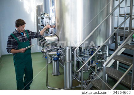 Male worker examining storage tank 34364603
